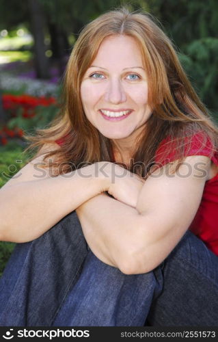 Portrait of smiling attractive mature woman relaxing in summer park