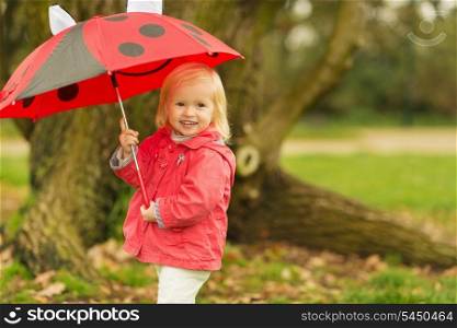 Portrait of smiling baby with red umbrella outdoors