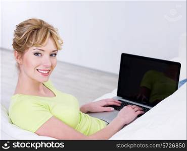 Portrait of smiling beautiful young woman using laptop at home - indoors