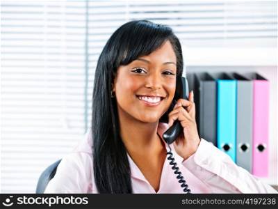 Portrait of smiling black business woman on phone in office