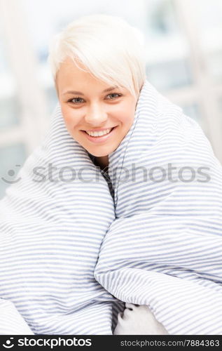 Portrait of smiling blonde woman wrapped in blanket