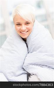 Portrait of smiling blonde woman wrapped in blanket