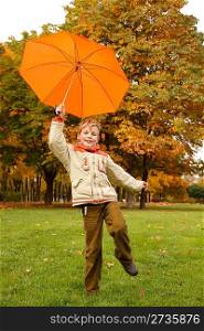 Portrait of smiling boy in autumn park. In hand umbrella, looks in camera.