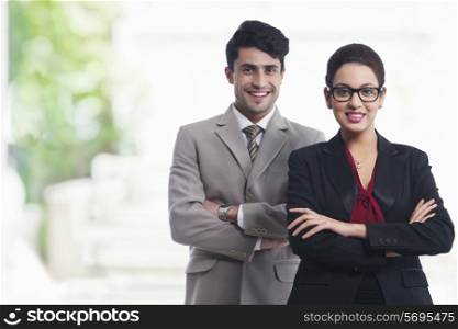 Portrait of smiling business colleagues standing arms crosses in office
