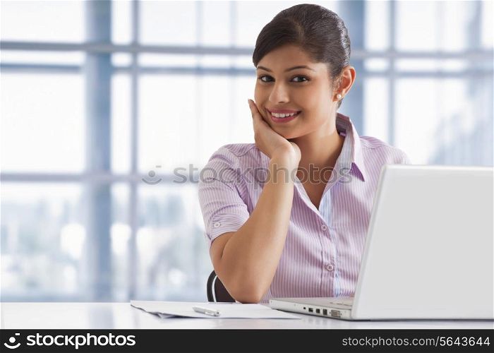 Portrait of smiling business woman at her desk with laptop