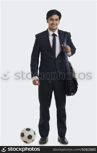 Portrait of smiling businessman carrying hand bag with football