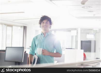 Portrait of smiling businessman having coffee in creative office