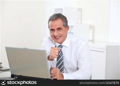 Portrait of smiling businessman in front of computer