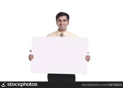 Portrait of smiling businessman showing empty placard over white background