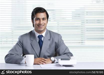 Portrait of smiling businessman sitting at office desk