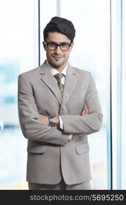 Portrait of smiling businessman standing arms crossed in office