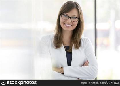 Portrait of smiling businesswoman standing with arms crossed at office