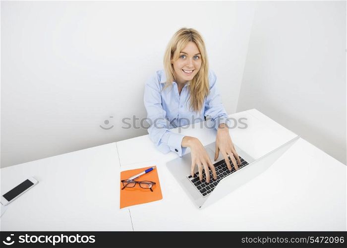 Portrait of smiling businesswoman using laptop in office
