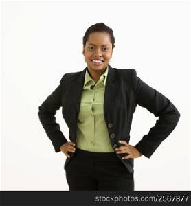 Portrait of smiling businesswoman with hands on hips against white background.
