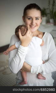 Portrait of smiling caring mother holding cute baby boy on hands