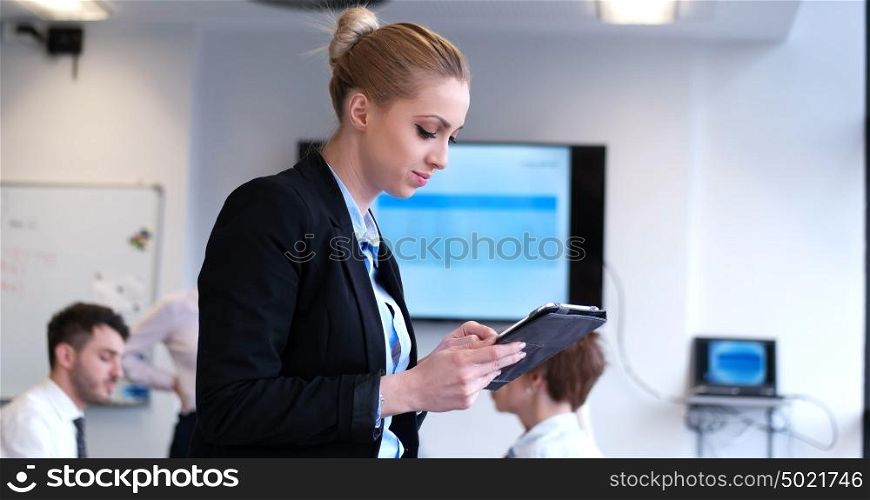 Portrait of smiling casual businesswoman using tablet with coworkers standing in background