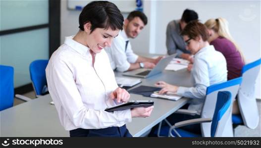 Portrait of smiling casual businesswoman using tablet with coworkers standing in background