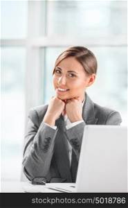 Portrait of smiling caucasian female executive working on laptop and making pause