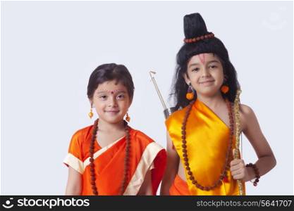 Portrait of smiling children dressed as Ram and Sita against white background