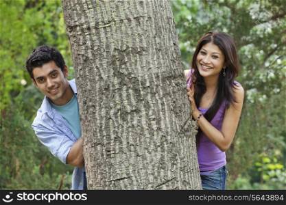 Portrait of smiling college students behind tree
