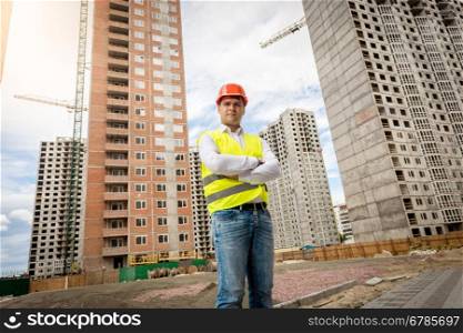 Portrait of smiling confident architect standing at buildings under construction