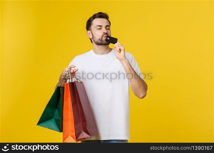 portrait of smiling couple holding shopping bags and credit card isolated on yellow background. portrait of smiling couple holding shopping bags and credit card isolated on yellow background.