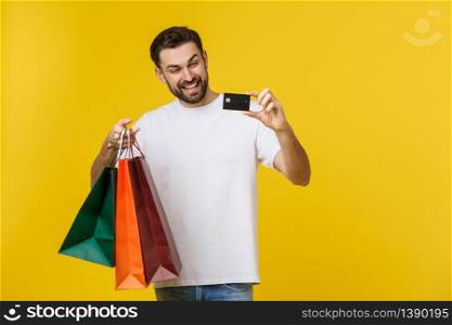 portrait of smiling couple holding shopping bags and credit card isolated on yellow background. portrait of smiling couple holding shopping bags and credit card isolated on yellow background.