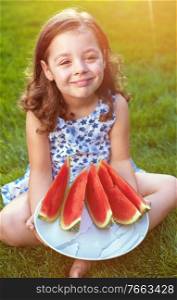 Portrait of smiling, cute girl holding watermelon slices in the garden