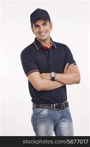 Portrait of smiling delivery man standing arms crossed against white background