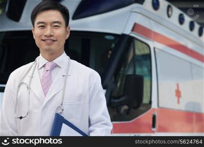 Portrait of smiling doctor holding clipboard in front of an ambulance