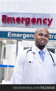 Portrait of smiling doctor outside of the hospital, emergency room sign in the background