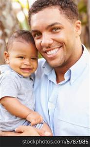Portrait Of Smiling Father Holding Baby Son Outdoors