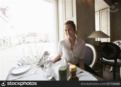 Portrait of smiling female customer sitting at restaurant table