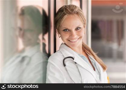 Portrait of smiling female doctor standing next to glass wall