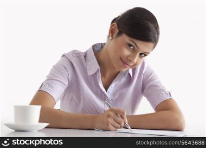 Portrait of smiling female executive writing on paper