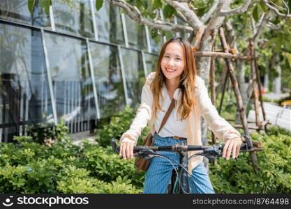 Portrait of smiling female lifestyle using bike in summer travel means of transportation, Happy Asian beautiful young woman riding bicycle on street outdoor near building city, ECO friendly concept