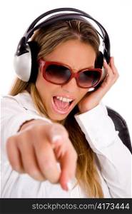 portrait of smiling female listening music and pointing at camera on an isolated background