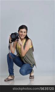 Portrait of smiling female photographer with camera in her studio
