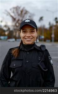 Portrait of smiling female police officer on street looking aside. Shot with blurred background. Portrait of smiling police woman on street