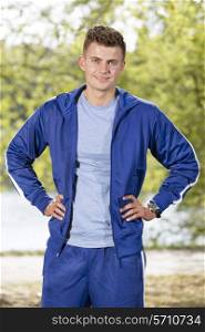 Portrait of smiling fit man standing with hands on hips in park