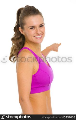 Portrait of smiling fitness young woman pointing back on copy space