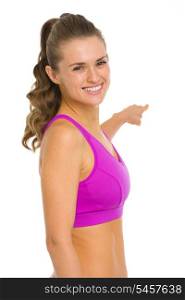 Portrait of smiling fitness young woman pointing back on copy space