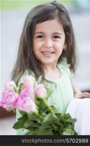 Portrait of smiling girl holding roses and gift box at home