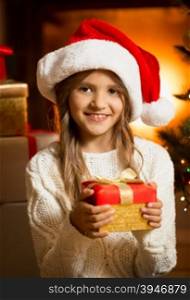 Portrait of smiling girl with Christmas gift at fireplace