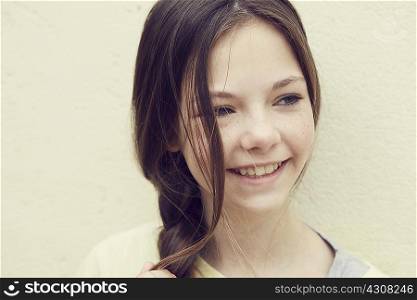 Portrait of smiling girl with plaited hair in front of wall