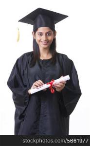 Portrait of smiling graduate student holding diploma against white background