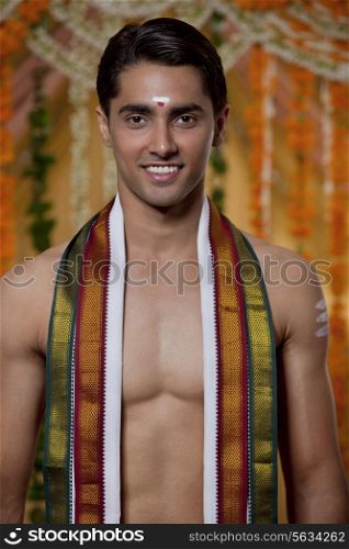 Portrait of smiling groom with flower decoration in background