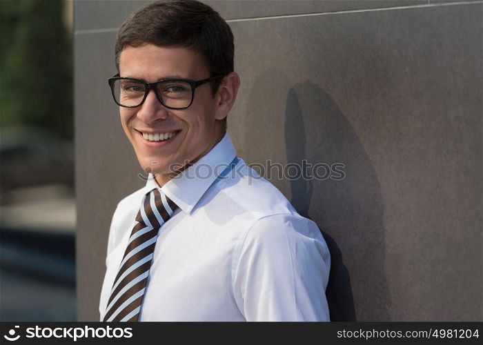 Portrait of smiling handsome businessman on the street looking at camera