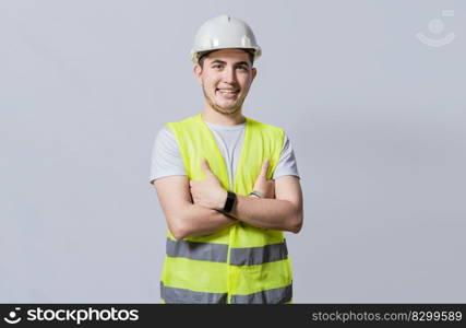 Portrait of smiling handsome engineer on white background, Portrait of young engineer wearing helmet and vest isolated. Young smiling engineer wearing helmet and vest with crossed arms isolated