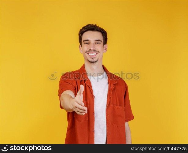 Portrait of smiling handsome man extend hand for handshake, look friendly, greet you, hi gesture, standing over yellow background